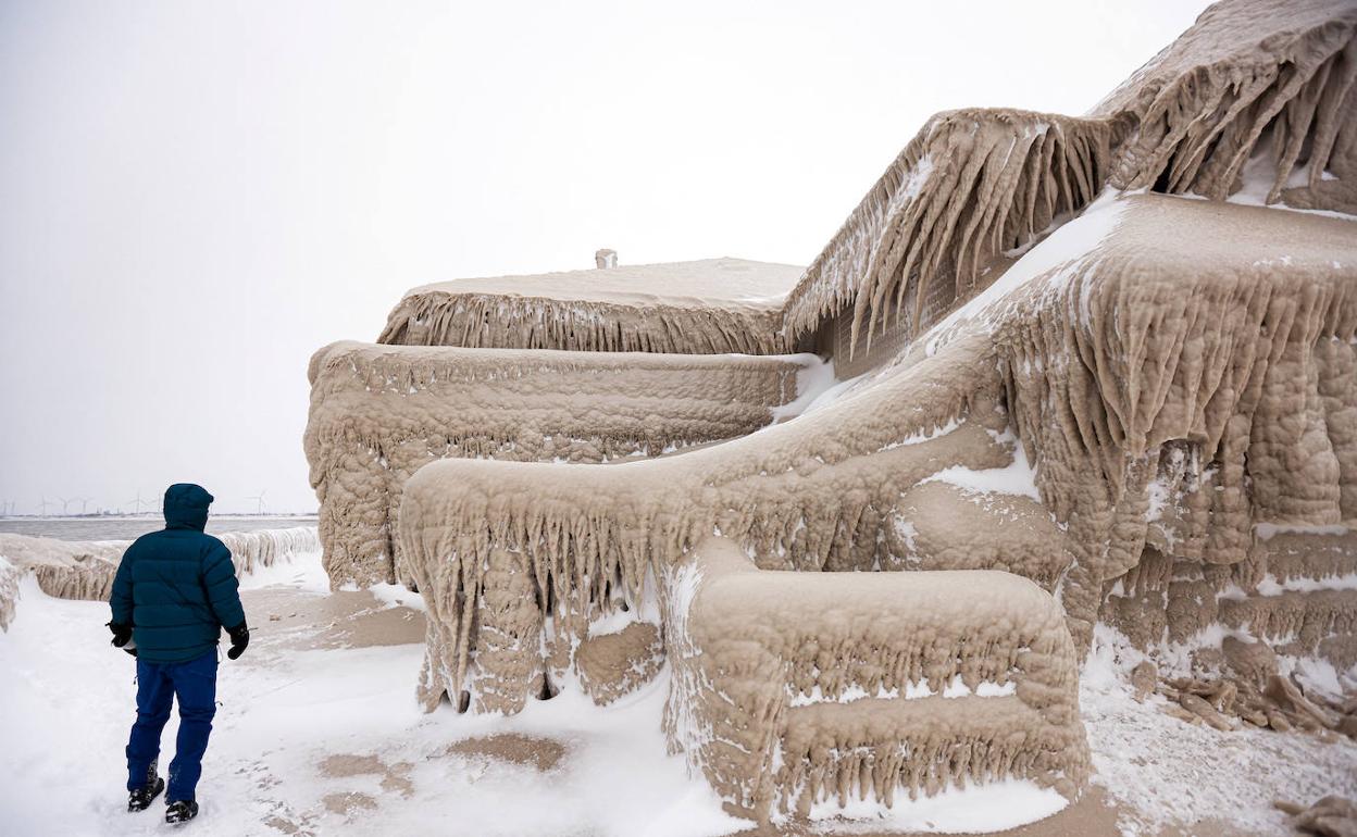 Un hombre camina junto al hielo formado por las olas del lago Erie, en Nueva York, que cubrieron un restaurante durante la tormenta que asola Estados Unidos este invierno. 