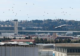 Vista de la torre de control del Aeropuerto de Málaga, con un avión despegando.