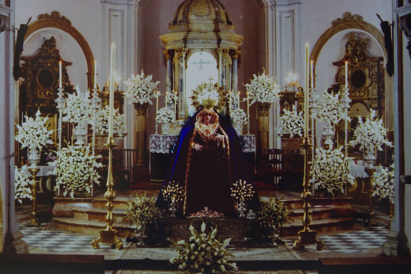 La Virgen del Patrocinio preside el altar mayor del templo de San Felipe Neri en 1986. Fue la tercera vez que ocupó este espacio, ya que en 1985 lo hizo por primera vez, para su bendición, y la segunda, para el besamanos de noviembre de ese año. El Nazareno aún no había llegado a la joven corporación.