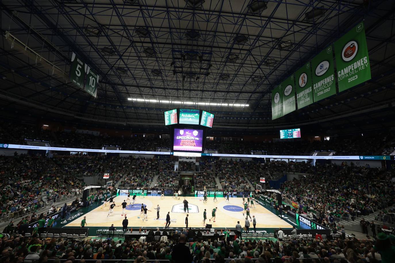 La previa del Unicaja-Girona estuvo marcada por la emoción: hubo fotos con la Copa, documental en el videomarcador e izado de la bandera con el nuevo título del club malagueño