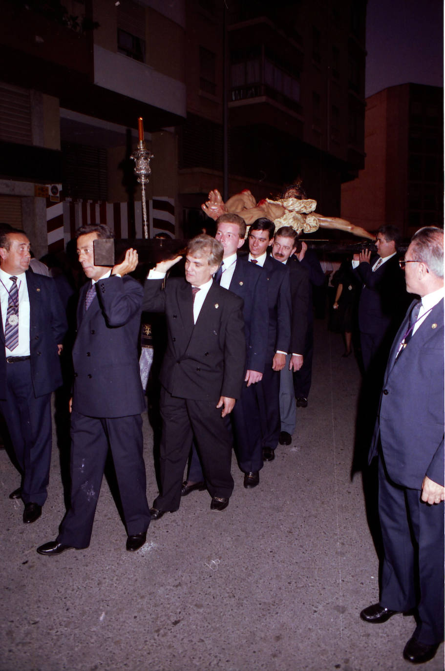 La primera salida procesional de la imagen del Cristo de la Crucifixión la constituyó el traslado que protagonizó el mismo día de su bendición, el domingo 19 de septiembre de 1993, desde el altar efímero que se instaló en la zona universitaria de El Ejido hasta la parroquia de El Buen Pastor. Portando las andas aparecen el tallista Manuel Toledano, el historiador Federico Fernández Basurte, el que fuera presidente de la Agrupación de Cofradías, Clemente Solo de Zaldívar, y Manuel Mérida-Nicolich, entre otros cofrades.