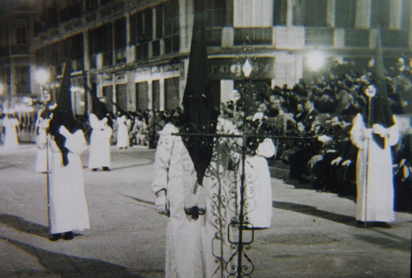 La primera cruz guía de la Hermandad de las Penas estaba realizada de forja. Como se aprecia en esta instantánea de mediados de los años 40 del siglo XX, el primitivo equipo de nazareno se componía de túnica blanca y capirote de color negro.