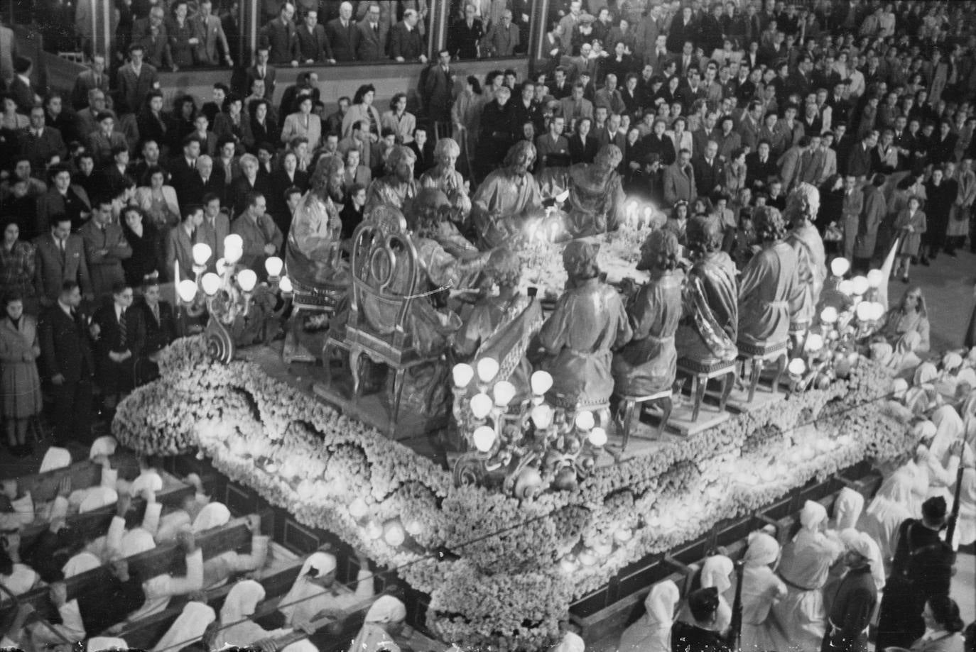 A pesar de la discreta calidad artística de las antiguas figuras de la Sagrada Cena y del recurrido trono de flores, muy en boga en la década de los años 40 del pasado siglo para tapar las carencias ornamentales, el conjunto que ofrecía el Señor rodeado del colegio Apostólico era realmente espectacular, por lo que no era extraño ver la tribuna oficial repleta de público.