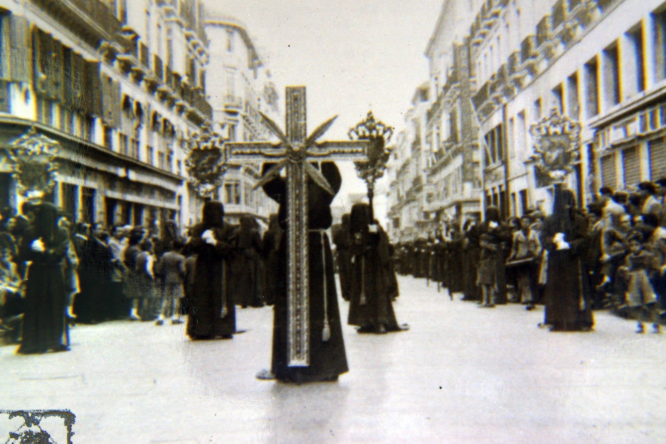 Frente de procesión de la Hermandad de Viñeros en calle Larios. Corría el año 1952. La antigua cruz guía, hoy expuesta en uno de los muros de la iglesia de Santa Catalina, estaba confeccionada con molduras de cuadro. A continuación, figuraban cuatro estandartes pictóricos, enmarcados en unas cartelas.