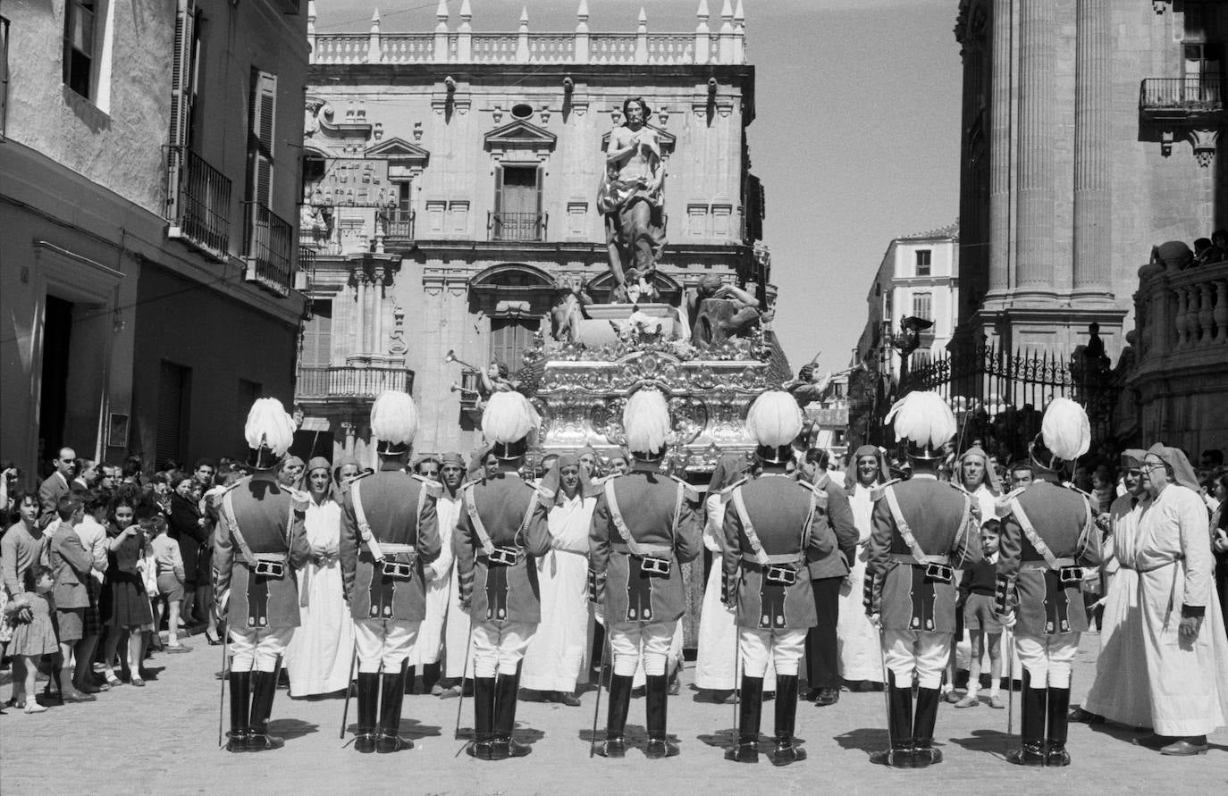 Policías locales vestidos de gala rinden honores al trono del Cristo Resucitado, detenido tras cruzar la plaza del Obispo en una soleada mañana de Domingo de Resurrección.