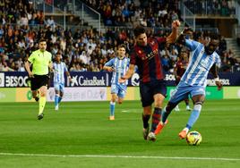 Una jugada del Málaga-Levante donde al fondo aparecen Febas y el colegiado De la Fuente Ramos.