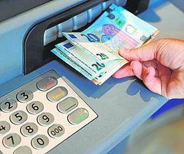 Una persona retira dinero en efectivo de un cajero, en una imagen de archivo.