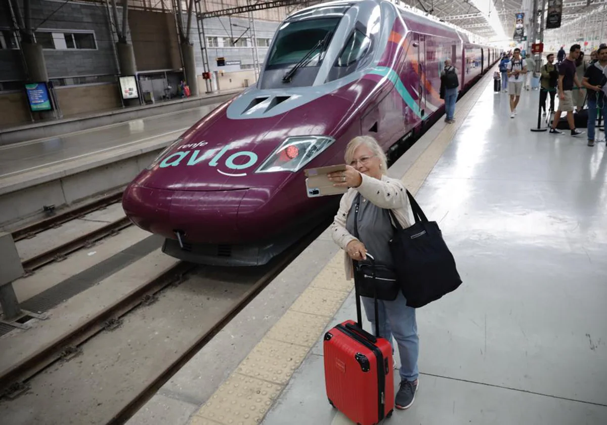 Una viajera se hace una foto con el nuevo tren de fondo.