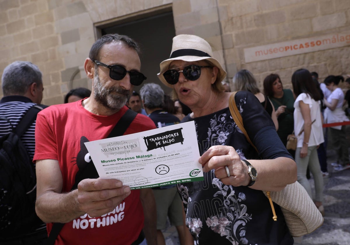 Dos turistas leen una octavilla repartida a las puertas del museo en una de las jornadas de huelga.