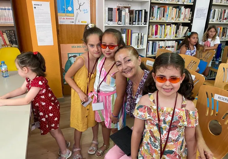 Las pequeñas Sara y Julia, con gafas, en la biblioteca de Almáchar, con otros menores.