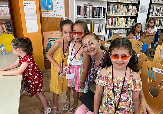 Las pequeñas Sara y Julia, con gafas, en la biblioteca de Almáchar, con otros menores.