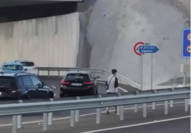 Un joven cruza el enlace de la autovía a pie.