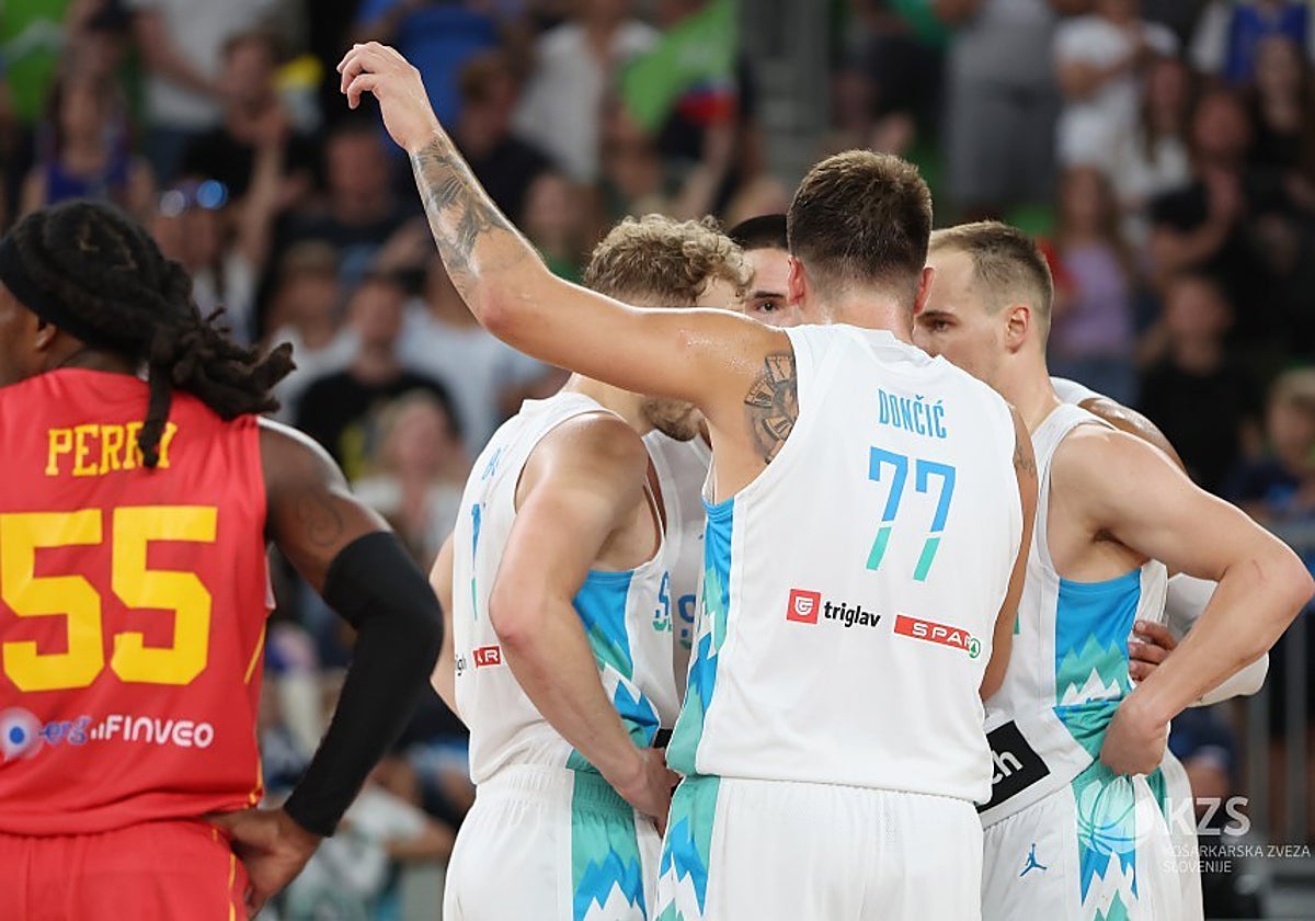 Doncic habla con sus compañeros con Perry cerca de los jugadores eslovenos.
