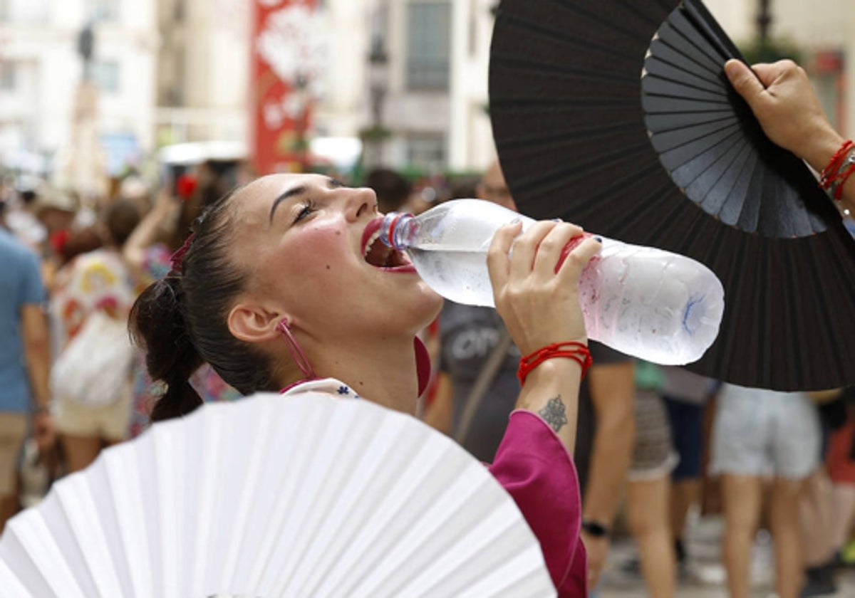 Agua y abanicos son remedios ideales para combatir el calor durante la feria de Málaga.