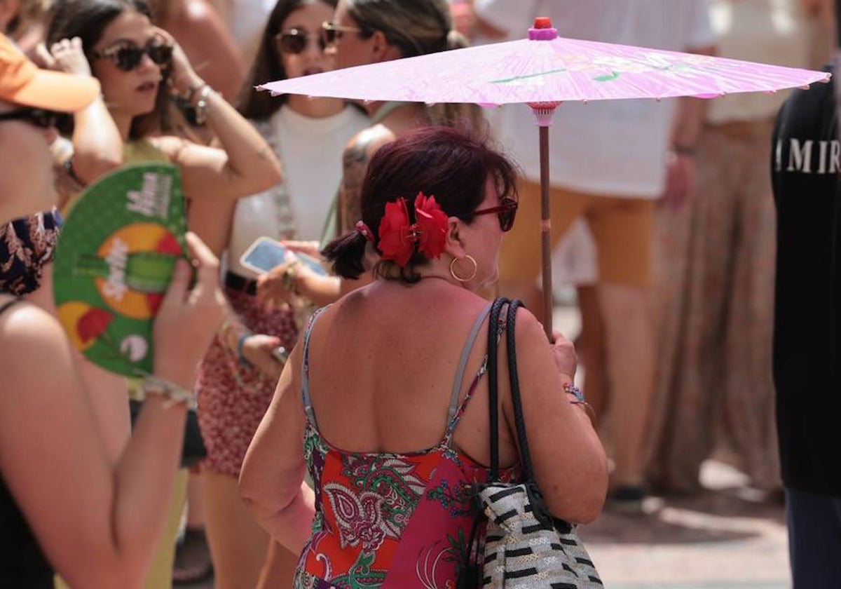 Una visitante se protege del sol bajo una sombrilla en la reciente feria.