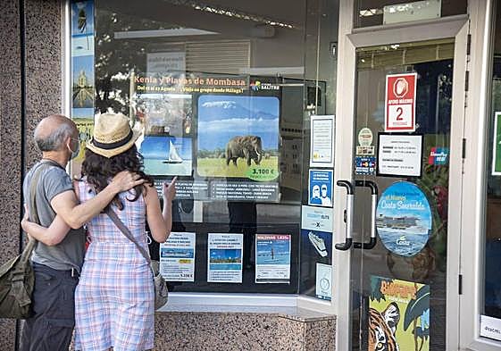 Una pareja mira el escaparate de una agencia de viajes de la Costa del Sol.