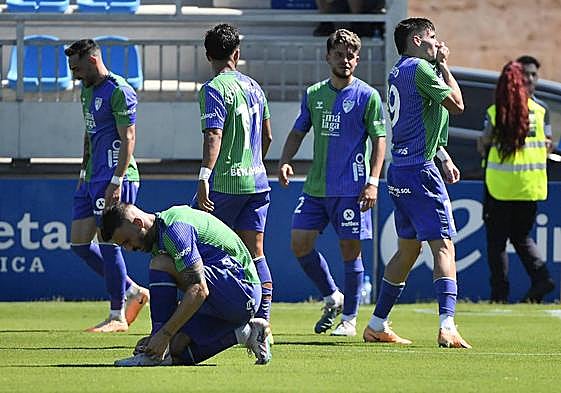 Roberto besa el escudo del Málaga tras marcar su gol ante el Atlético Baleares mientras Dioni se anuda las botas.