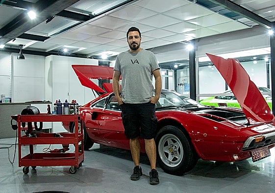 Álvaro González junto a un Ferrari 308, una de los tantísimas joyas que pasan por su local a diario.