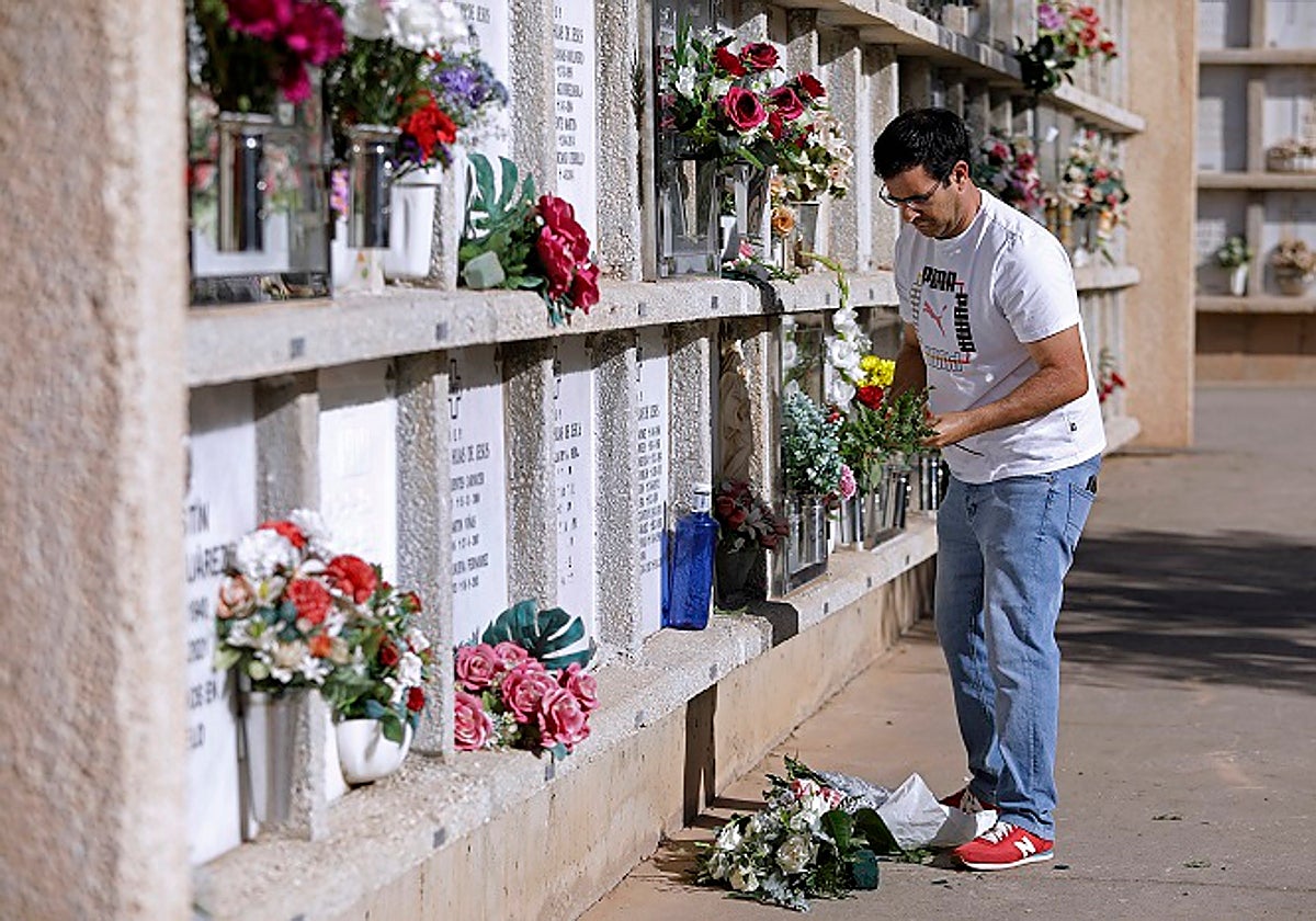 Un hombre pone flores a sus seres queridos en uno de los nichos de San Gabriel.