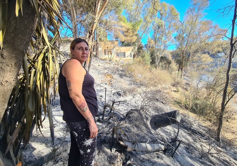 Rocío, delante de la zona de monte quemada y con su vivienda al fondo.