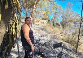 Rocío, delante de la zona de monte quemada y con su vivienda al fondo.