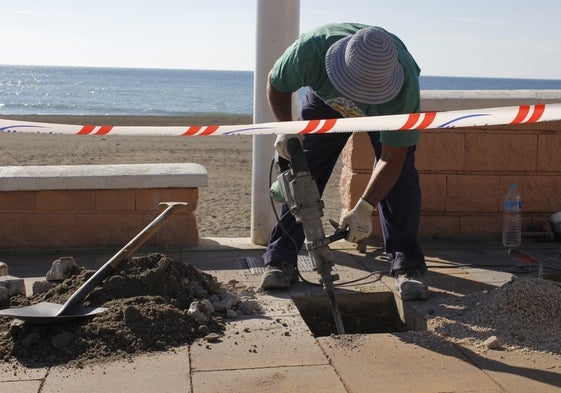 Un operario realiza trabajos en el Paseo Marítimo de Rincón de la Victoria, donde se ha ejecutado una obra para la construcción de una tubería que conecta la estación de tratamiento de aguas residuales del Peñón del Cuervo con el municipio, para mejorar el abastecimiento en la comarca.