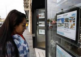 Una mujer mira los anuncios de una inmobiliaria en Málaga.