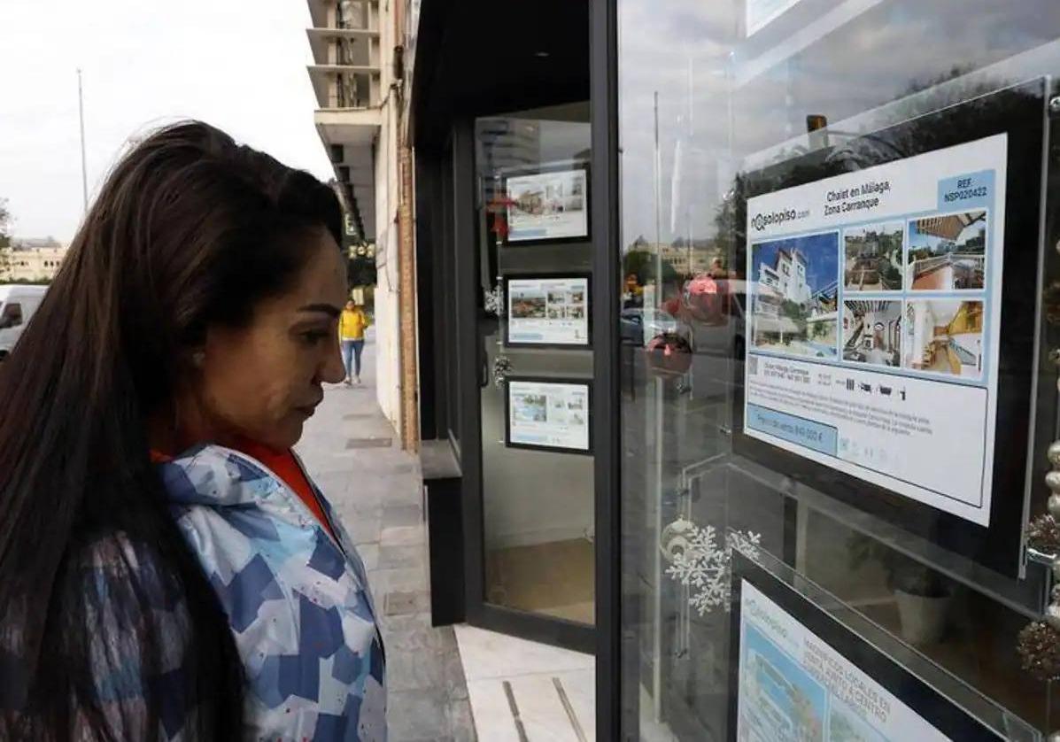 Una mujer mira los anuncios de una inmobiliaria en Málaga.