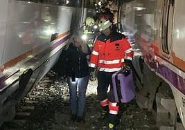 Pasajeros ayudados por bomberos tras salir del tren.