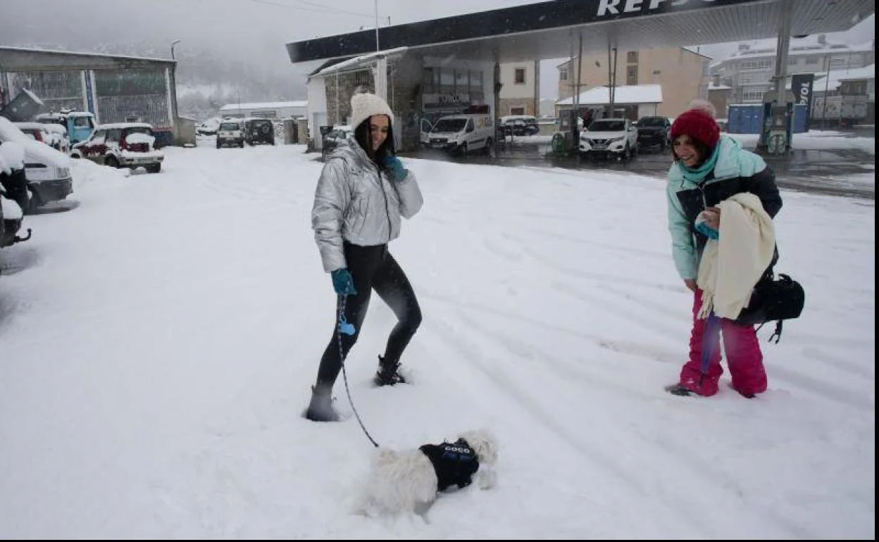 Dos mujeres caminan con su perro por una calle cubierta de nieve, a 26 de enero de 2023, en Pedrafita do Cebreiro, Lugo, Galicia 