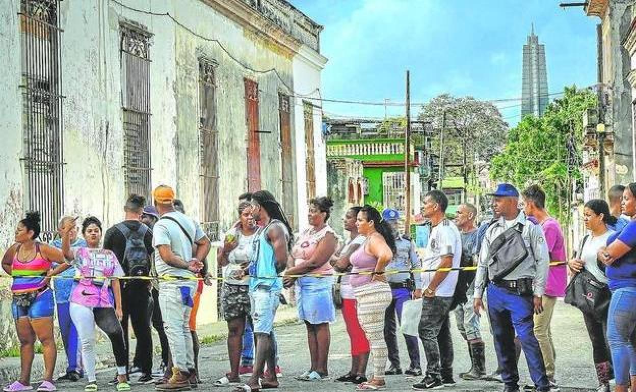 Una fila de cubanos siguen los trabajos de reparación de los daños ocasionados por el huracán 'Ian' en la localidad de El Cerro