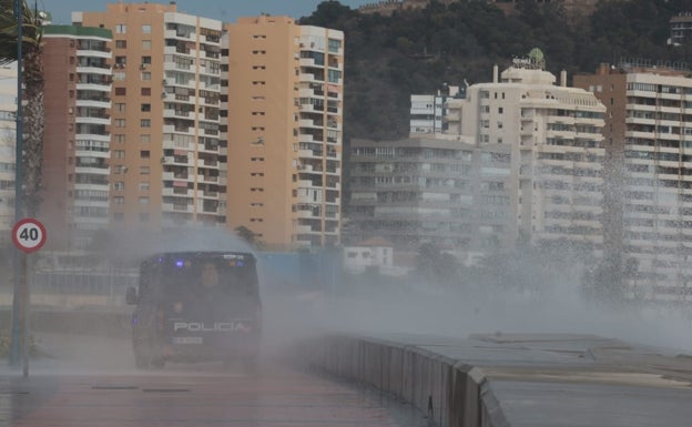 El agua salta por encima del espigón y llega hasta el paseo de la Farola por el viento en Málaga. 