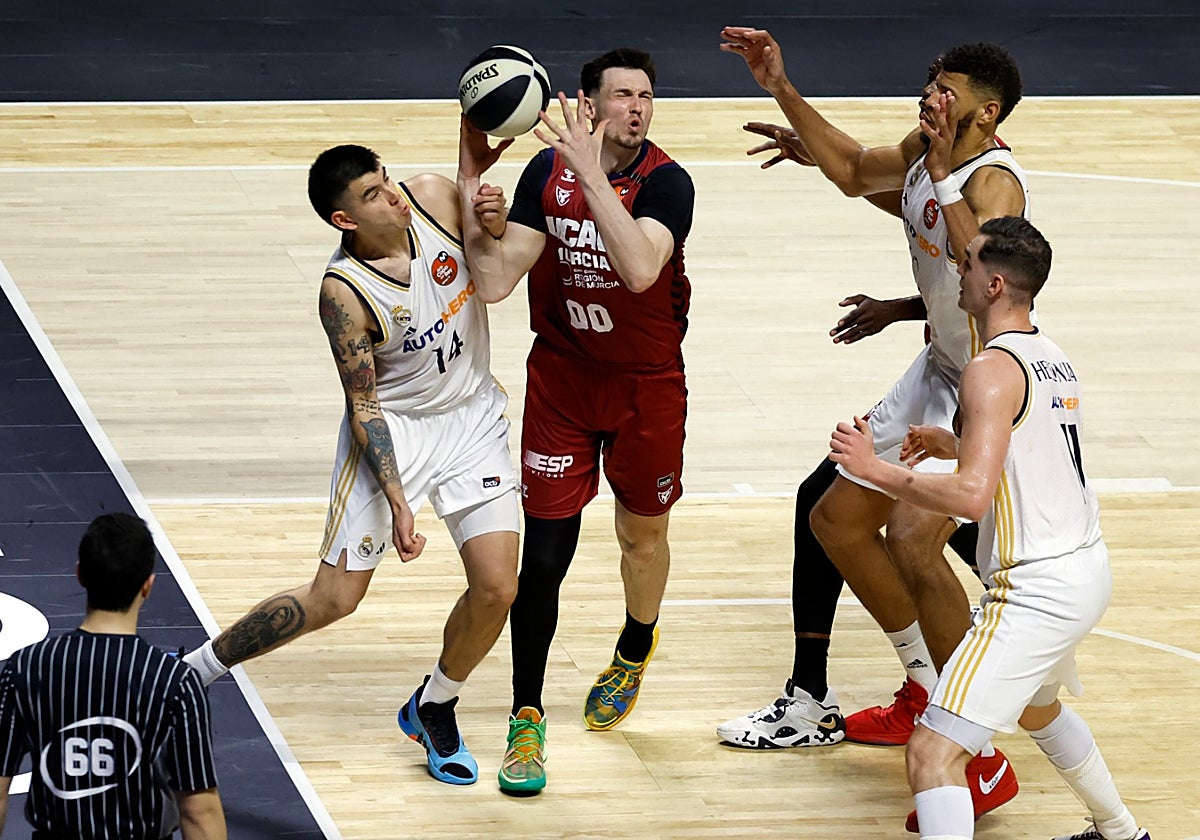 Kurucs pelea por un rebote rodeado de jugadores del Madrid.