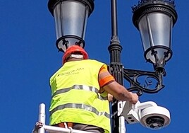 Un operario instala una cámara en una farola.