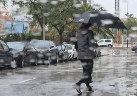 Una persona camina bajo un paraguas en Málaga capital, esta mañana.