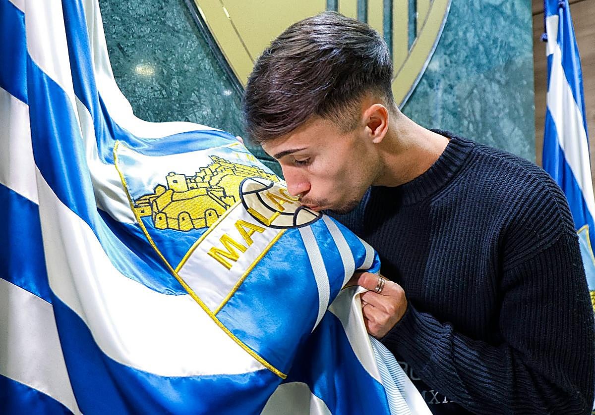 David Larrubia besa el escudo del Málaga en la presentación oficial de su renovación con el club hasta 2027.