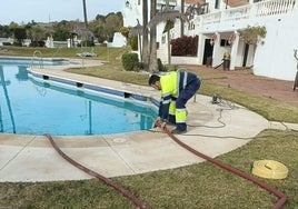 Un operario municipal retira el agua de la piscina de una comunidad de vecinos, que decidió donarla al Ayuntamiento de Benalmádena ante la actual situación de sequía.