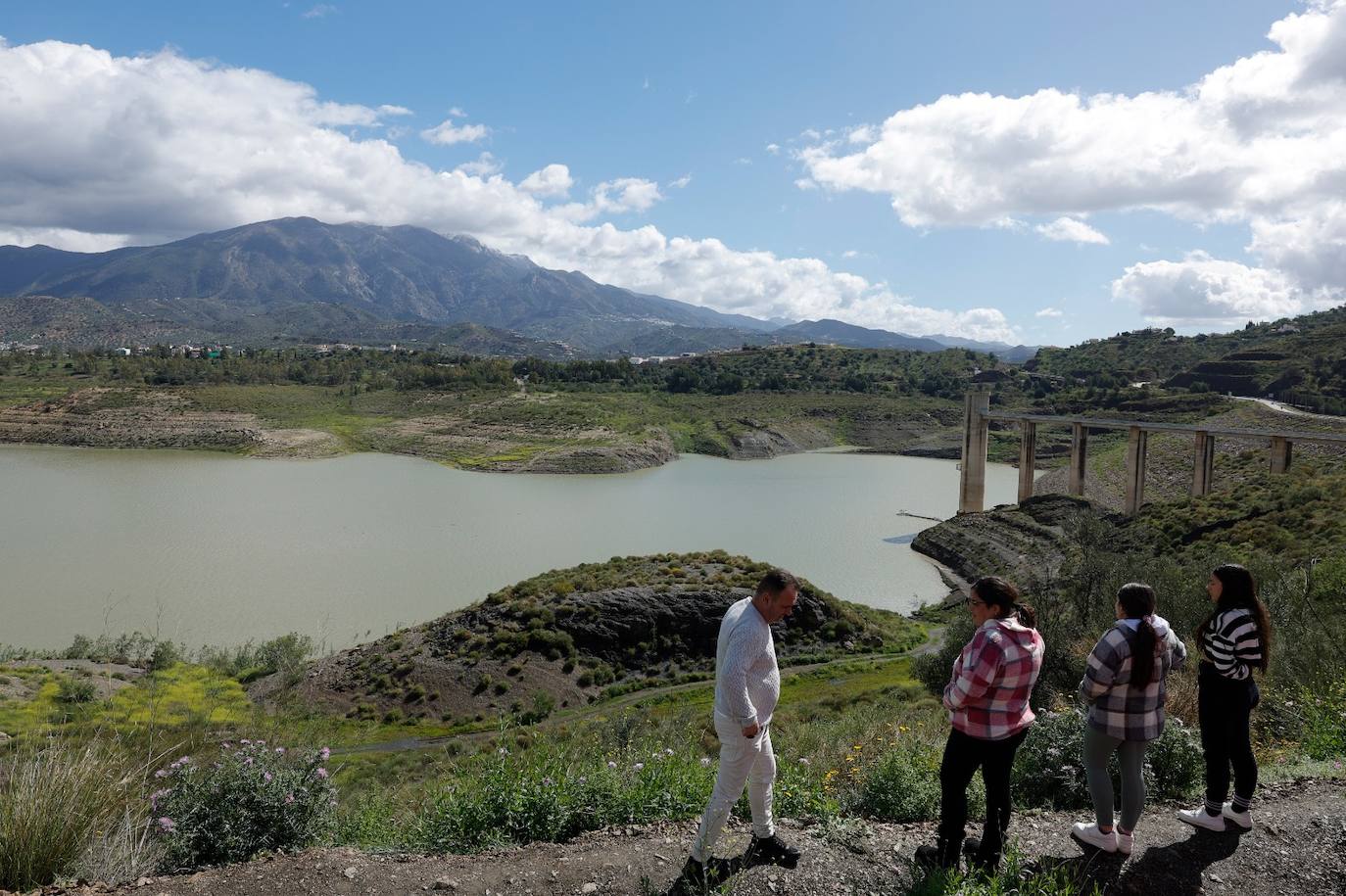 Un grupo de personas observa el pantano, que tiene unas bombas instaladas por la sequía.