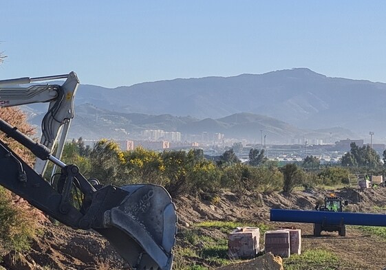 Maquinaria trabaja en el Camino del Puente del Rey, en suelo alhaurino, con la vista de Málaga al fondo.