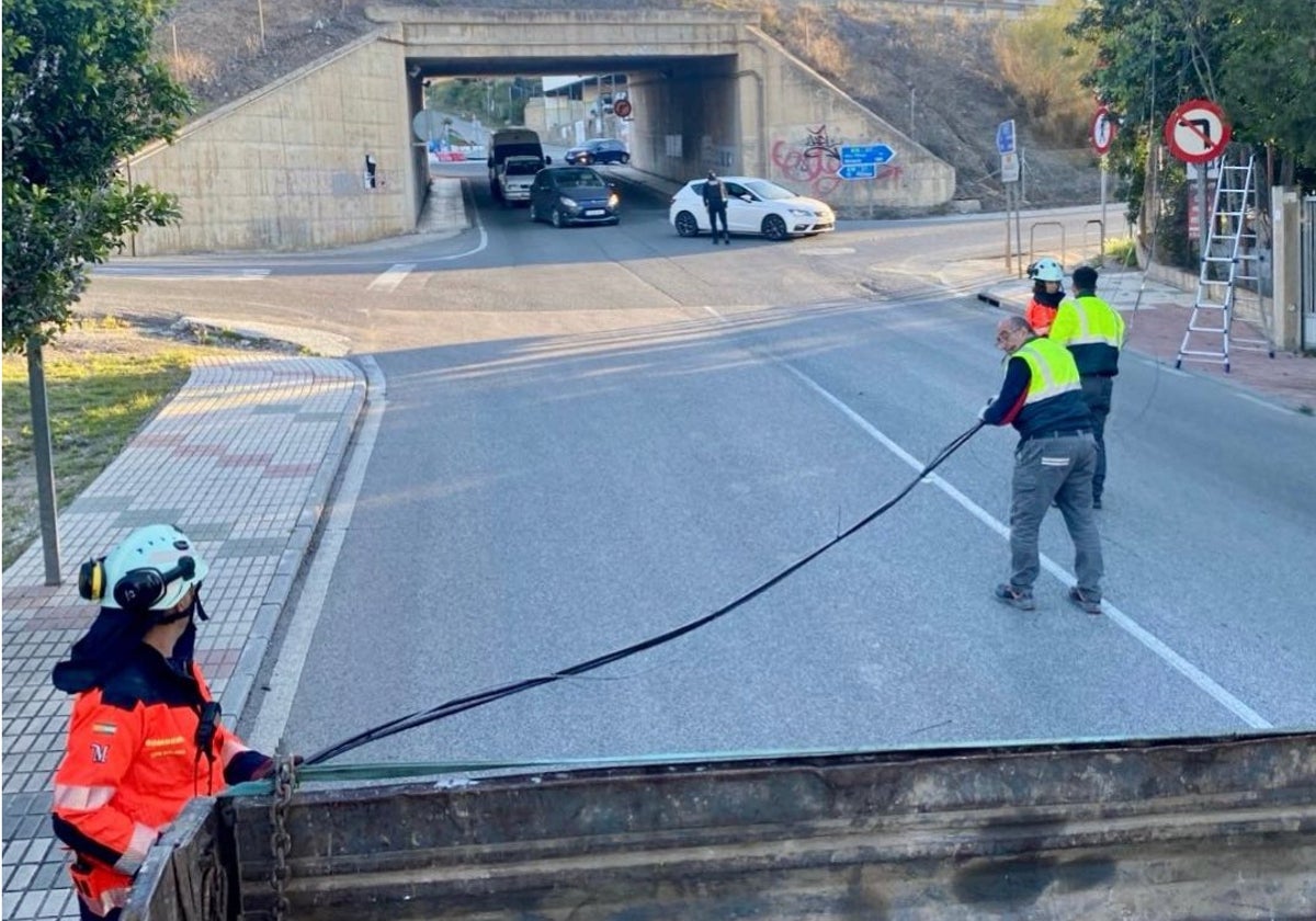 Bomberos y personal de la compañía suministradora retiran el cableado, cuya caída ha complicado el tráfico en el Carril de los Toros, que enlaza con la autovía A-7.