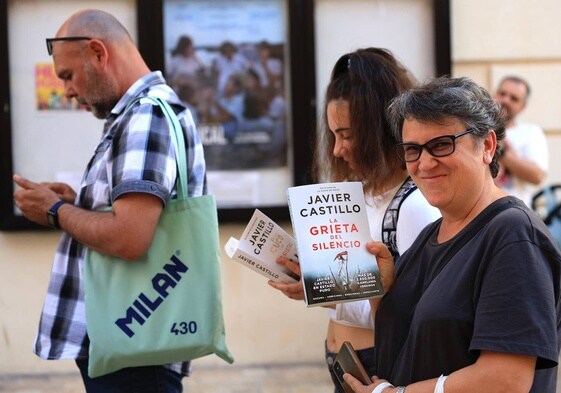 Lectores leyendo el nuevo libro de Castillo mientras hacían cola antes de la presentación en el Aula SUR.