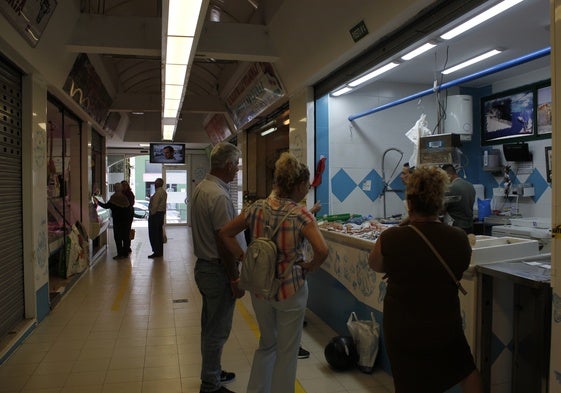 Compras en el mercado, donde hay bastantes persianas bajadas.