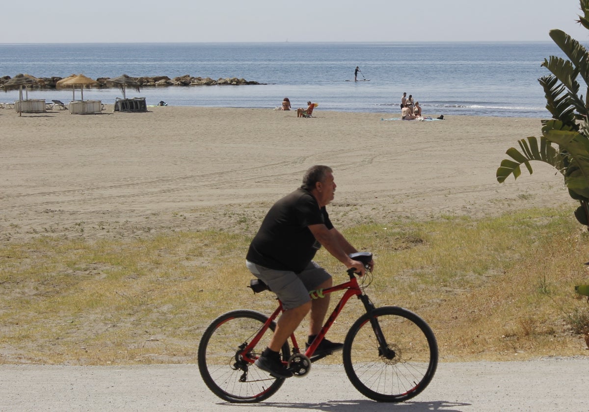 Un ciclista y bañistas en la playa de La Cala del Moral.