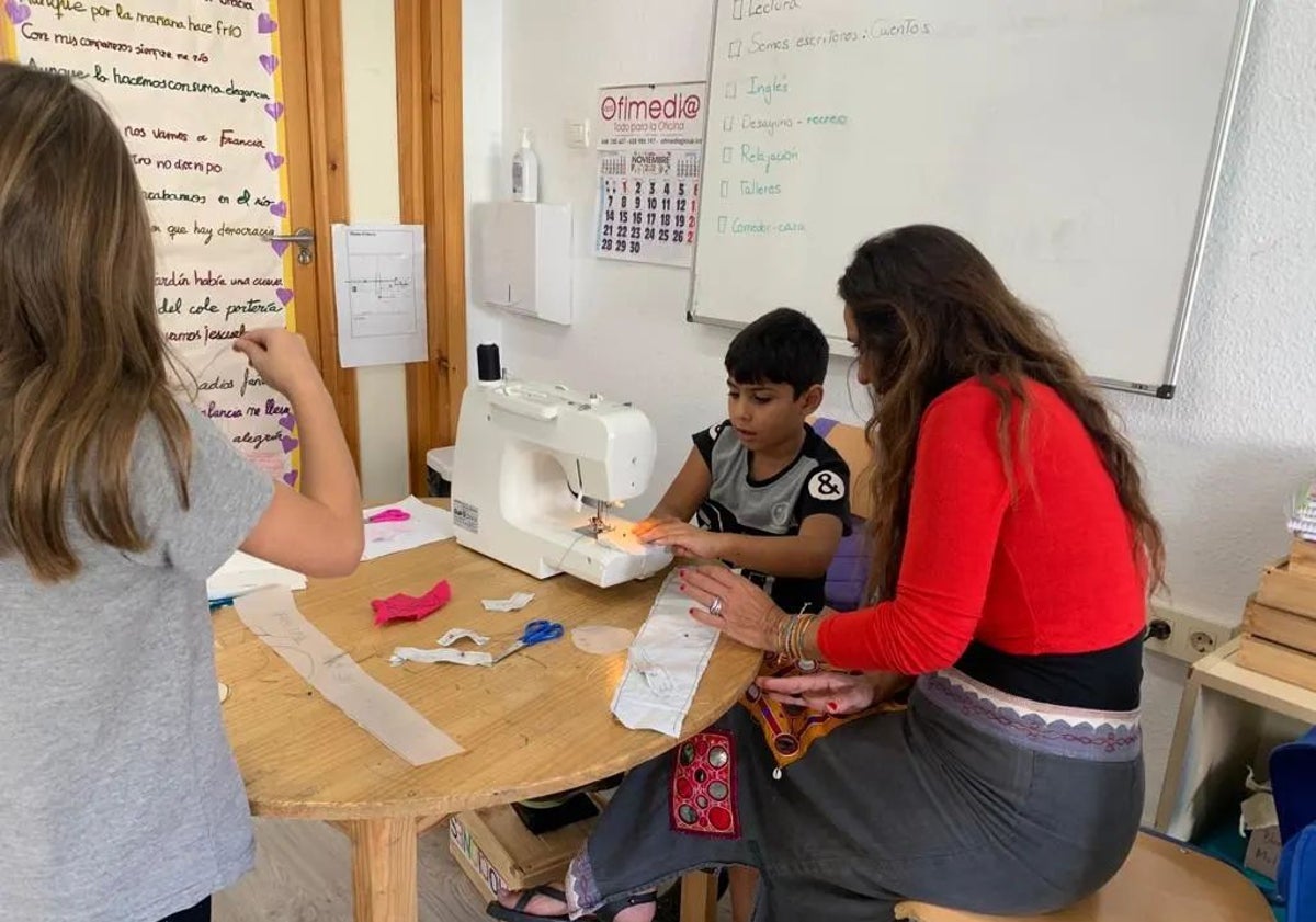 Imagen principal - Taller de costura. Conchi dio a los alumnos lecciones de patronaje y una niña toma medidas a una alumna de San Telmo.