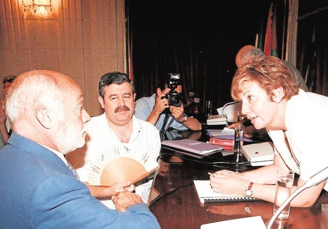 Romero, con un abanico, observa al socialista Martín Toval, mientras la alcaldesa popular Celia Villalobos hablaba con él en un pleno del Ayuntamiento de Málaga.