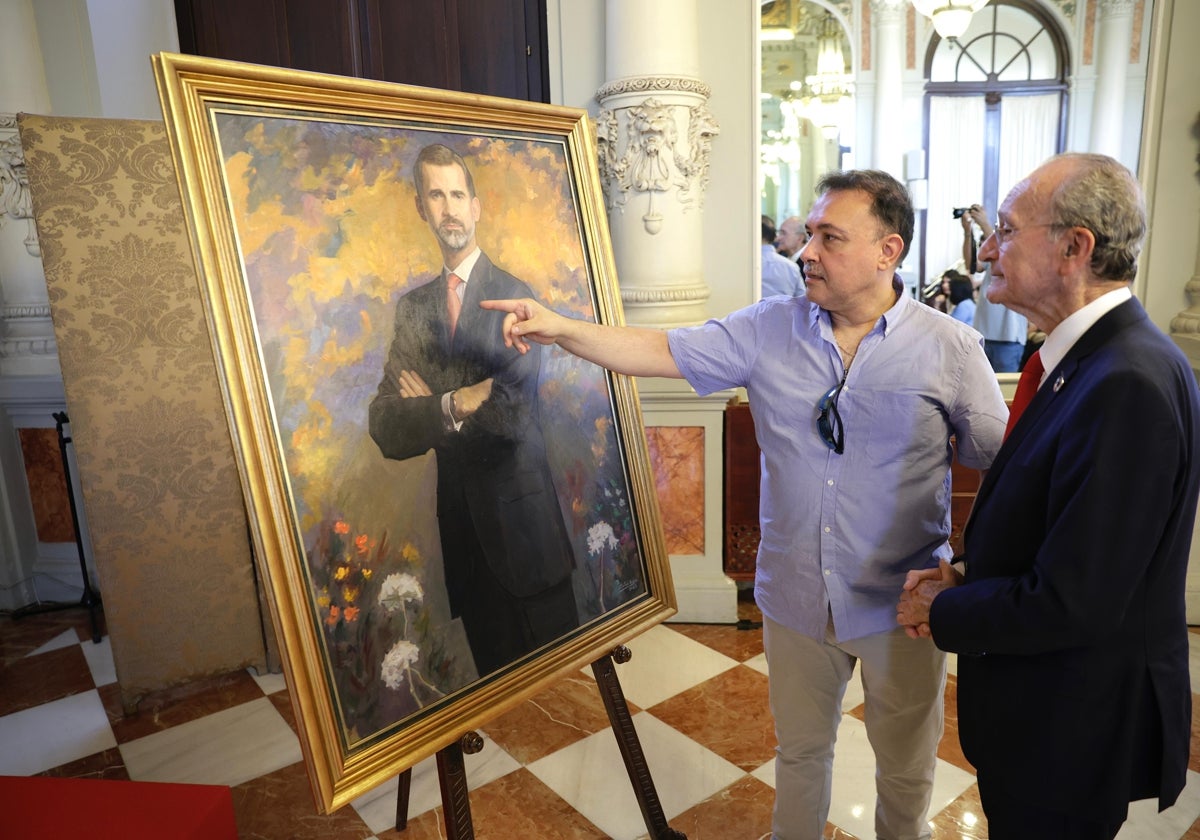 El pintor, Cristóbal Gómez Córdoba, le explica al alcalde de Málaga los detalles del retrato de Felipe VI, en el salón de los Espejos.