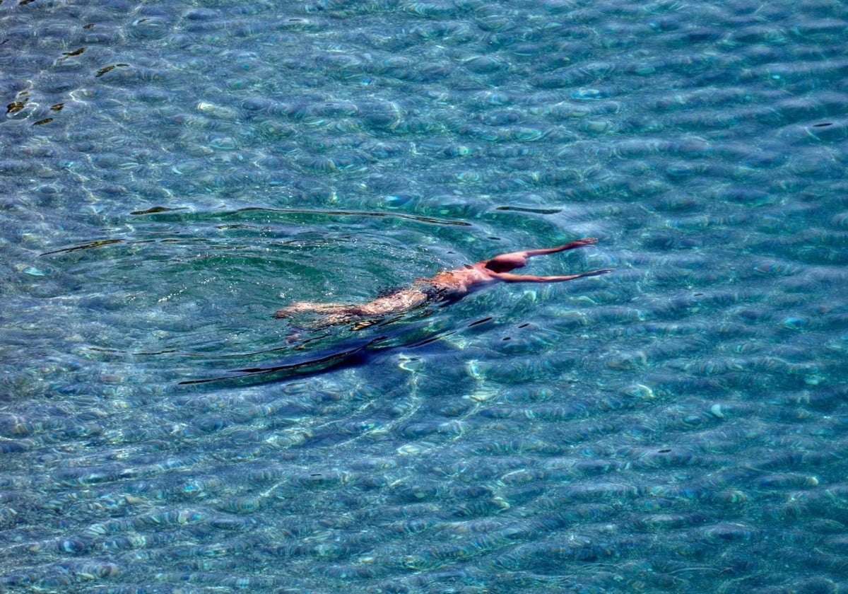 Un hombre disfruta de un baño en una playa de la provincia de Málaga.