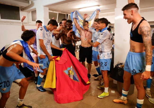 Los jugadores del Málaga celebran el ascenso con un capote con el escudo del club.