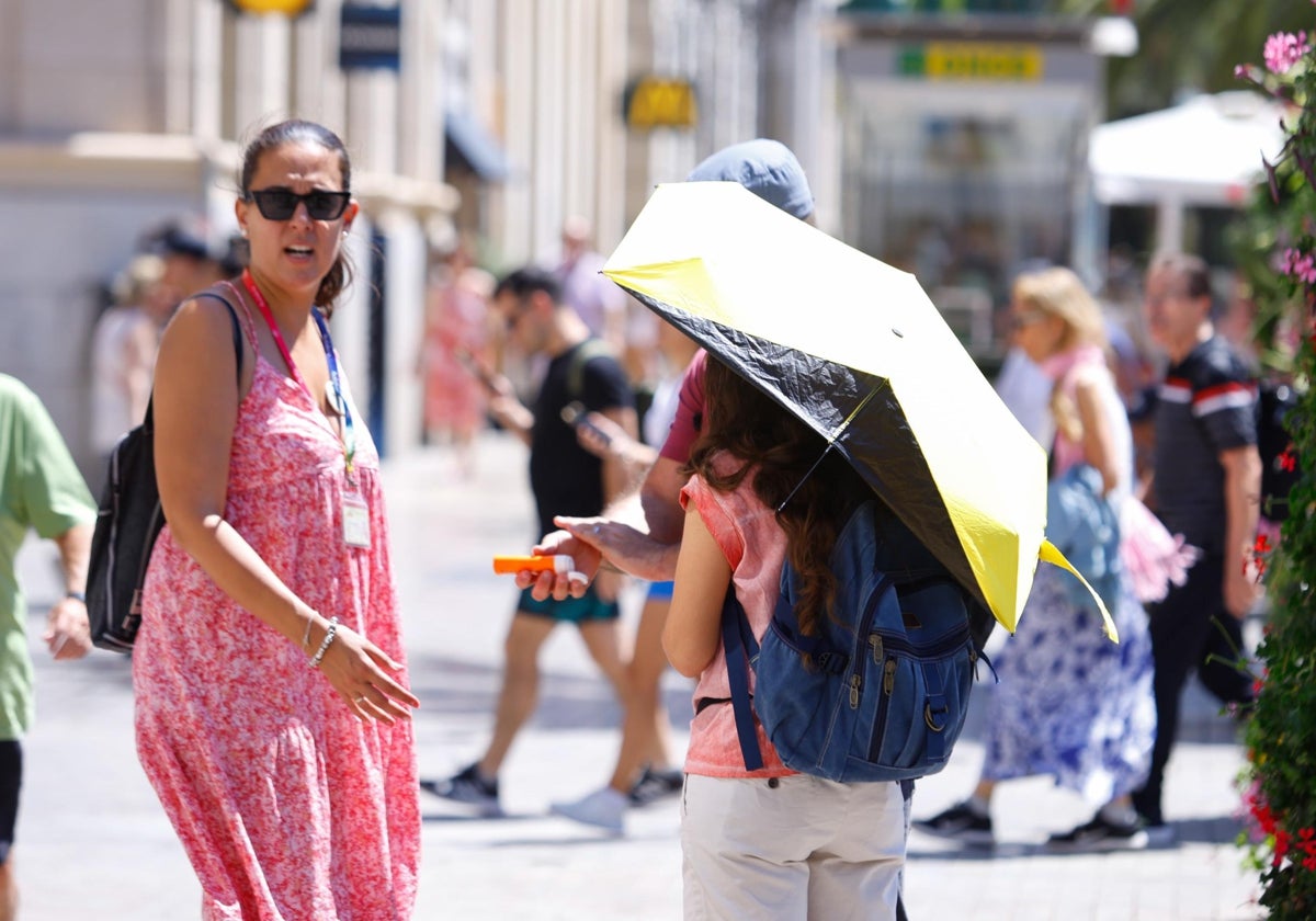 Una turista se protege del sol debajo de una sombrilla en el Centro de Málaga.