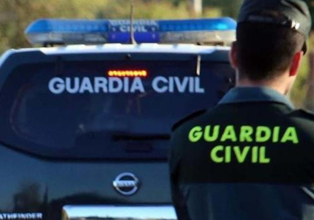 Imagen de archivo de un agente de la Guardia Civil junto a un coche patrulla.